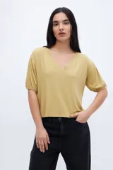 Remera color mostaza con escote en V, mangas abullonadas y corte cropped.