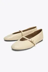 Bailarinas color crema de piel con tira delantera con hebilla y acabado en punta redonda.