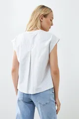 Remera blanca de corte holgado con cuello en V y mangas cortas. Presenta detalle de tela a rayas verticales en los laterales con botones decorativos.