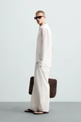 Camisa de manga larga color celeste claro, con cuello solapa y cierre frontal de botonadura. Presenta una textura sutil en el tejido.