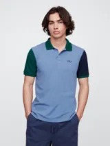 Chomba manga corta celeste con cuello verde, detalle de color verde en una manga y azul marino en la otra. Logo de la marca Gap bordado en el pecho.