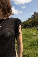 Musculosa tejida color marrón con diseño calado y flecos en los hombros.