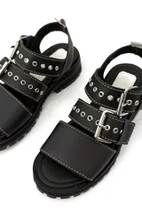 Sandalias negras de cuero con hebillas plateadas, suela track y costuras blancas.