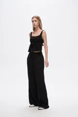 Pantalón negro de viscosa, corte ancho y tiro alto, con elástico en la cintura y bolsillos laterales.
