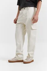 Pantalón cargo color beige, de corte recto, con bolsillos laterales y traseros. Se ajusta a la cintura con cinturón de cuero marrón.
