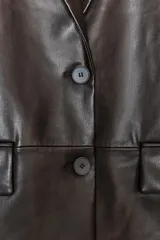 Blazer marrón oscuro de efecto piel, con cuello solapa y manga larga. Tiene bolsillos de plastrón en la parte delantera, forro interior a tono y cierre frontal con botones.
