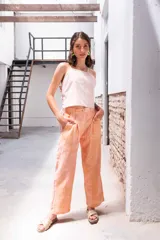 Pantalón de lino color salmón con estampado de rayas verticales, tiro alto, pinzas delanteras, bolsillos laterales y corte holgado.