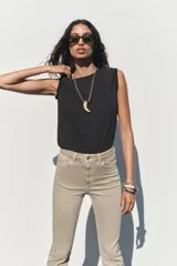 Pantalón de jean color beige, de tiro alto, corte ajustado en la cadera y muslos, y acampanado desde la rodilla. Tiene cinco bolsillos y cierre frontal con cremallera y botón.
