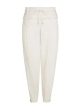 Pantalón jogger color crudo con estampado a cuadros, cintura con cordón ajustable, ribete elástico y minivolantes, bolsillos delanteros, detalles plisados y bajo con botones laterales.