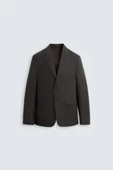 Blazer negro de corte relaxed fit, confeccionado en tejido de algodón con acabado ligeramente encerado. Tiene cuello con solapas de muesca, manga larga con puños abotonados, bolsillo de vivo en el pecho, bolsillos de solapa en la cadera, bolsillo interior, aberturas en la espalda y cierre frontal con botones.