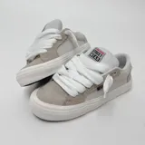 Zapatillas bajas de skate Vision Street Wear, color beige y blanco, con capellada de gamuza y lona, cordones gruesos blancos y suela de goma blanca. Logo de la marca en la lengüeta y lateral.