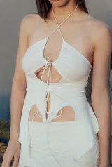 Top blanco con escote halter y volados en el ruedo, con tiras finas que se atan en el cuello y en el centro del pecho.