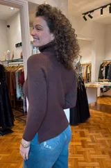 Polera color crema de cuello alto y tejido de punto acanalado.