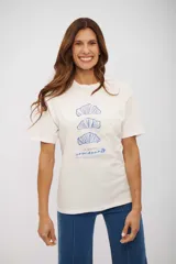 Remera de manga corta color blanco hueso, con cuello redondo y un estampado central en azul que muestra tres ilustraciones de croissants y el texto "LE MATIN croissants".