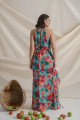 Vestido largo de gasa de seda natural con estampado floral en tonos verde y rojo. Tiene corte en la cintura, falda con volados y tajo delantero.