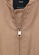 Chaqueta bomber color beige con cierre frontal, cuello mao y puños elásticos.