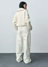 Abrigo corto color crudo de tejido bouclé con mezcla de lana. Tiene cuello de solapa ancha, cierre delantero con cremallera, manga larga con puños elásticos y terminaciones de canalé en contraste. Diseño oversize.