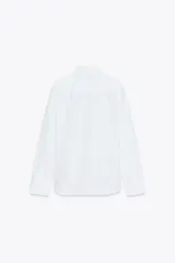 Camisa blanca de popelina de algodón, con cuello solapa y mangas largas con puños abotonados.