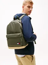 Mochila Tommy Jeans Essential color verde militar con base color beige. Tiene un compartimento principal con cierre, un bolsillo frontal con cierre, asa superior y correas acolchadas ajustables.