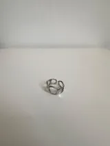 Anillo plateado de acero quirúrgico hipoalergénico con diseño irregular y aberturas circulares.