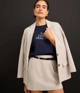 Short pollera de sastrería confeccionado en polivelour color beige. Tiene trabillas en la cintura, cierre por cremallera delantero, recorte en V en la parte trasera de la cintura, pliegues y pinzas delanteras. Incluye cinturón fino de material sintético con hebilla.