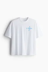 Remera deportiva blanca de corte boxy, confeccionada en tejido funcional DryMove™ que ayuda a absorber el sudor. Tiene cuello redondo ribeteado y hombros levemente caídos. Estampado en el frente con flechas y el número 012 en color celeste.