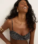 Top de bikini negro con estampado de lunares blancos, corte media taza con breteles ajustables y lazo en la espalda. Confeccionado en microfibra.