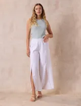 Pantalón blanco de lino con pretina ancha elastizada en punto smock, pierna ancha y ruedo con tajo.