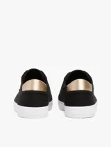 Zapatillas Tommy Hilfiger de lona negra con suela blanca de goma y talón dorado metalizado.