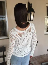 Sweater calado color crudo, de manga larga y cuello redondo.