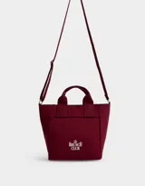Cartera mini de lona color crudo con estampado "The Brunch Club" en azul marino. Tiene correa regulable y desmontable, manijas superiores y cierre superior.