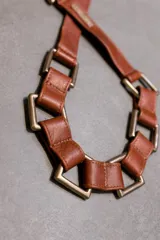 Cinturón de cuero marrón con hebilla metálica de gran tamaño con forma cuadrada.