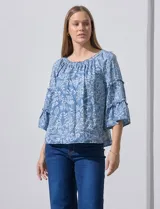 Blusa celeste con estampado floral blanco, escote con frunces y mangas 3/4 con volados.