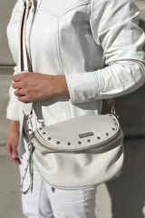 Bandolera de cuero vacuno color blanco, con correa de cinta regulable, forro de algodón, cierre central y bolsillo trasero con cierre.