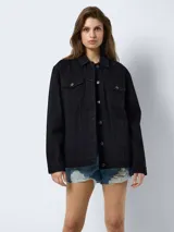 Chaqueta de jean negra de corte oversize, con cuello clásico, cierre frontal con botones metálicos, bolsillos delanteros con solapa y botón, y mangas largas.