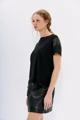 Remera blanca de lino con mangas cortas y calce al cuerpo. Presenta cadenas de strass en los hombros.