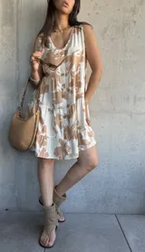 Vestido corto color beige con estampado de hojas marrones, escote en V, botones frontales y volados en ruedo.