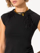 Top negro de tejido de punto con cuello redondo y mangas cortas estilo raglán. Presenta plumas aplicadas en el frente y logo bordado en la espalda.