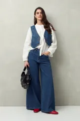 Pantalón de jean negro de calce ultra wide leg, tiro alto y silueta amplia desde la cadera hasta el bajo. Diseño clásico de cinco bolsillos y cierre con botón metálico y cremallera.