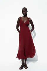 Vestido midi color borgoña con escote en V, tirantes anchos con detalle de nudo y falda plisada. Cierre trasero con cremallera oculta.