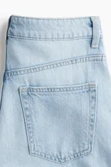 Jean celeste de denim rígido de algodón con cinco bolsillos, corte wide leg, cintura extra alta, cierre con botón y largo levemente largo. Inspirado en los 70.