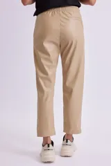 Pantalón de cuero sintético color beige con cintura elástica y cordón ajustable.