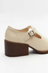 Zapato tipo T-bar de charol negro con hebilla lateral y taco ancho.