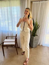 Chaleco tejido color arena con terminaciones en punto festón negro.