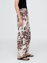 Pantalón jean tiro alto, corte amplio y estampado animal print de vaca en tonos marrones y blancos.