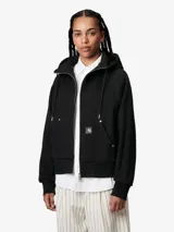 Campera negra con capucha ajustable, cierre frontal con cremallera, bolsillo tipo canguro con remaches metálicos y logo cuadrado en el frente.