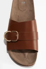 Sandalias marrones de cuero sintético con hebilla dorada ajustable y plantilla anatómica.