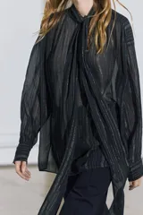 Blusa negra con cuello redondo con lazo en el mismo tejido, manga larga con puño y detalle de hilo metalizado.
