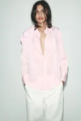 Camisa blanca de lyocell con cuello solapa, manga larga y bajo asimétrico. Cierre frontal con botones.