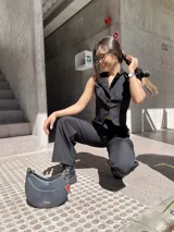 Conjunto sastrero negro compuesto por un chaleco con botones y un pantalón de corte recto.